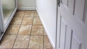 Een badkamer met een witte deur, een douchecabine van glas en een betegelde vloer.
