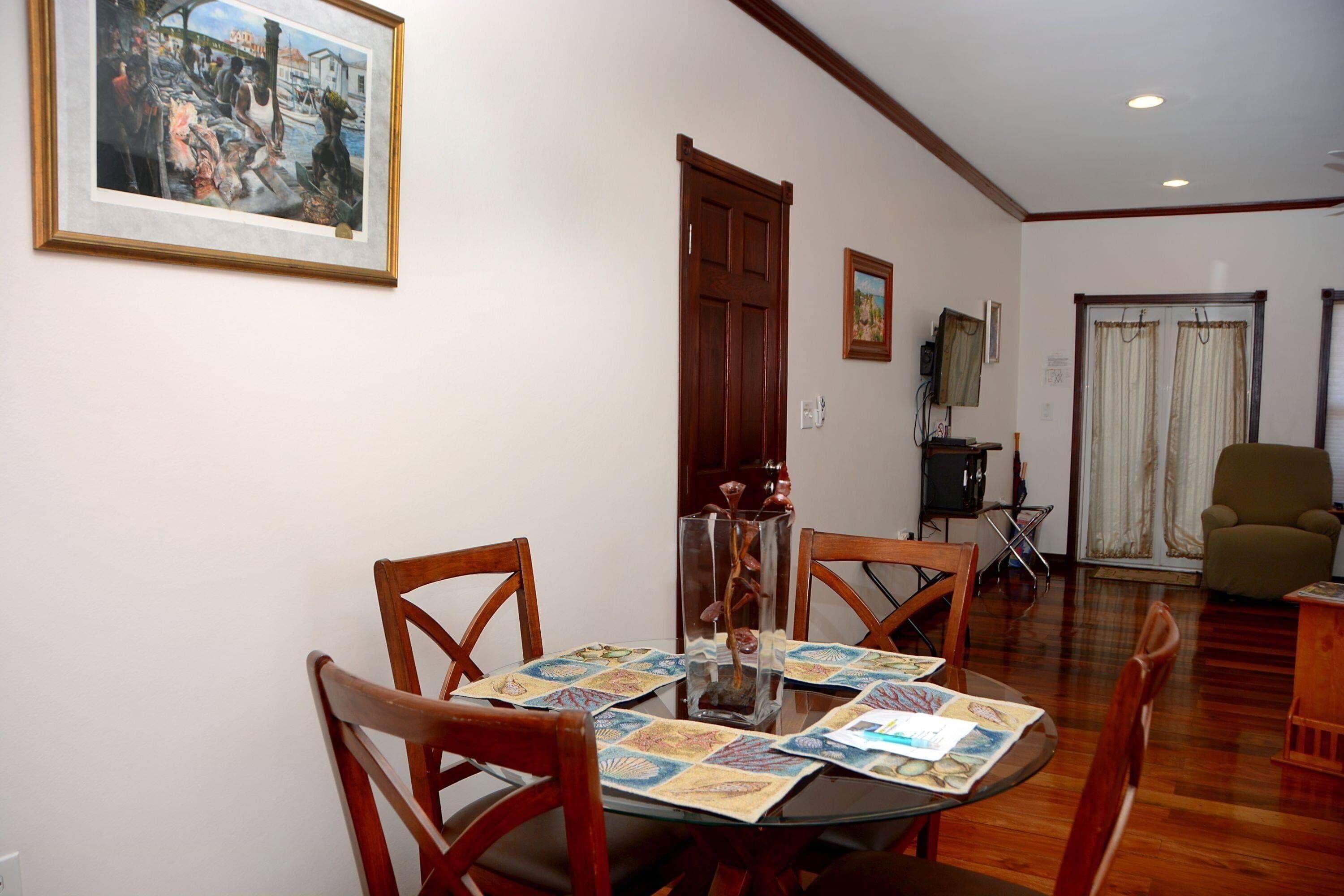 A dining area with a round table, wooden chairs, and a glass centerpiece.