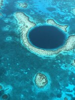 Vista aérea de una zona costera con una extensa laguna central rodeada de arrecifes de coral y pequeñas islas.