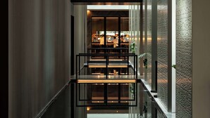 A modern interior with a glass railing, a seating area, and a view of a bar area. - Park Hyatt Auckland (Auckland)