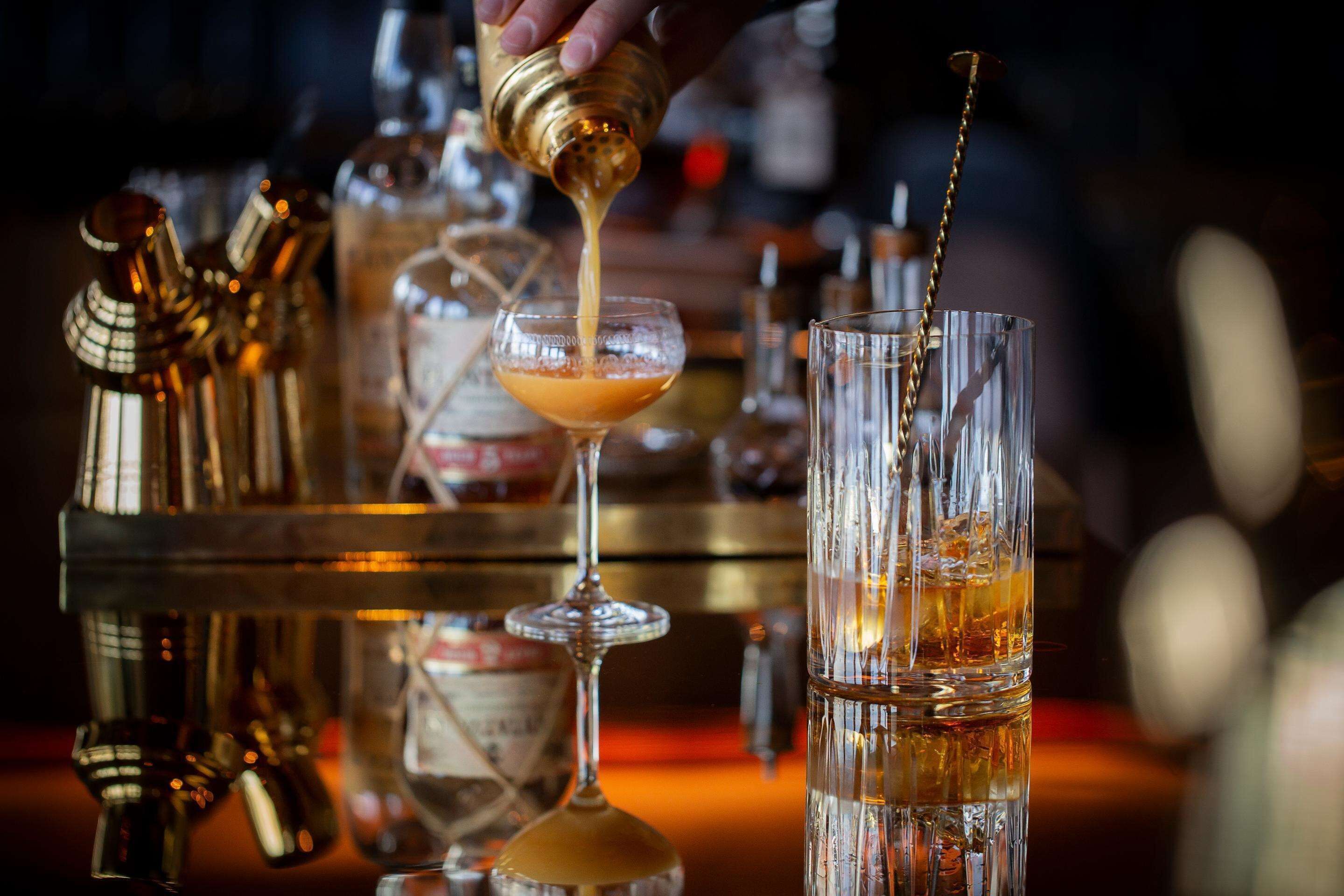 En bartender hælder en drink op i et glas.