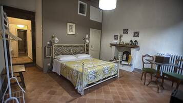 A bedroom with a bed, bedside table, lamp, and a small table with chairs.