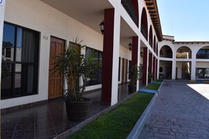 A building with a covered walkway, potted plants, and numbered doors.