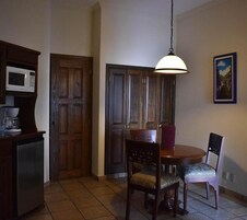 Un comedor con mesa de madera, sillas, lámpara colgante y microondas en un mueble.