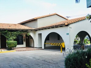 A building with a tiled roof, a covered walkway, and a yellow barrier. - Hotel Sand's San Luis Potosí (San Luis Potosi)