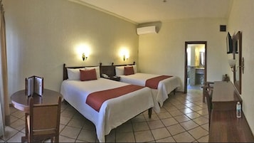 Habitación de hotel con dos camas, un escritorio y una silla.
