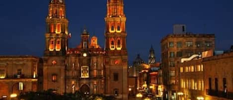 A historic building with two prominent towers, surrounded by urban streets and buildings.
