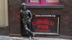 Eine Statue einer Person neben einem Schild für The Cavern Pub in Liverpool.