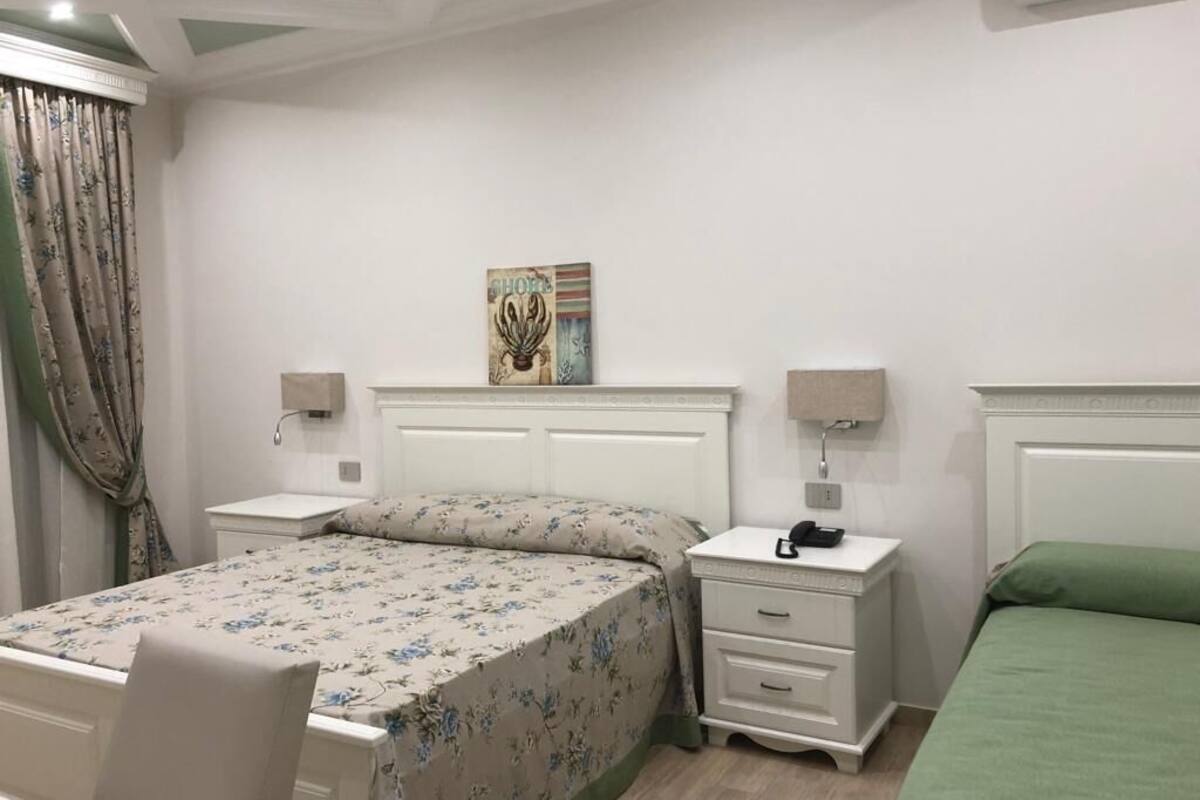 Ein Schlafzimmer mit einem Bett, Nachttischen, einem Sessel und einem an der Wand hängenden Kunstwerk.