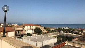 A coastal residential area with houses, a street lamp, and a view of the sea. - Stella del Mare (Licata)