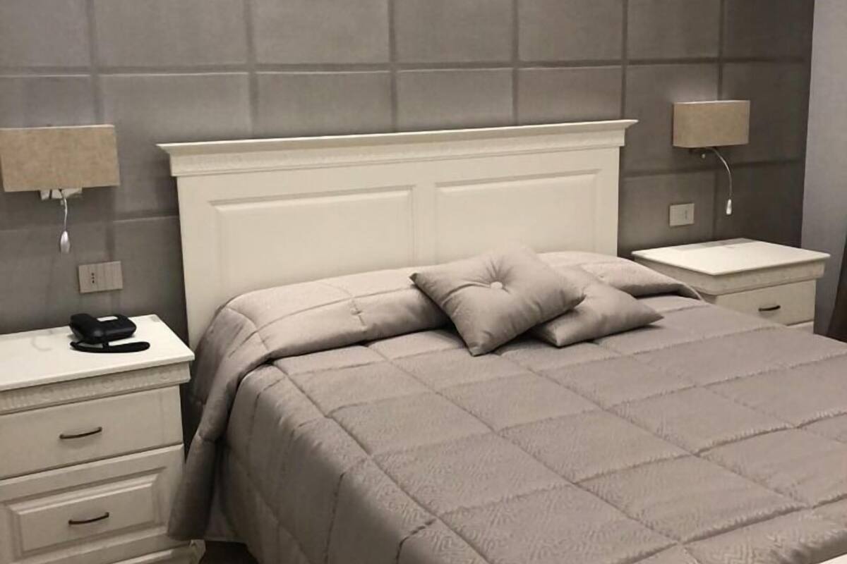 Ein Schlafzimmer mit einem Bett, zwei Nachttischen, einer Kommode und einer Wandlampe.
