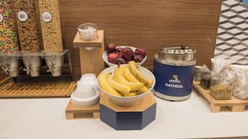 Un bufé de desayuno con cereales, frutas y recipientes de avena.