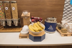 A breakfast buffet with cereal, fruits, and oatmeal containers. - Holiday Inn Express & Suites Fort Wayne North by IHG (Fort Wayne)