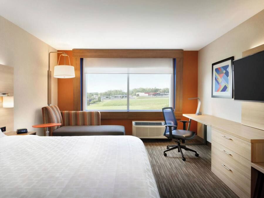Habitación de hotel con cama, escritorio, silla, televisión y ventana con vistas al exterior.
