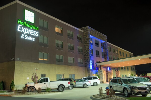 Un hotel Holiday Inn Express & Suites con estacionamiento y varios vehículos.