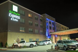 Un hotel Holiday Inn Express & Suites con estacionamiento y varios vehículos.