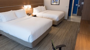 Una camera d'albergo con due letti, un comodino, una lampada e un quadro appeso al muro.