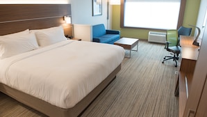 Una camera d'albergo con un letto grande, un divano blu, un tavolino e una scrivania con una sedia.