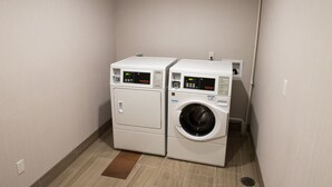 A laundry room with two stacked appliances, one dryer and one washer, with digital displays.