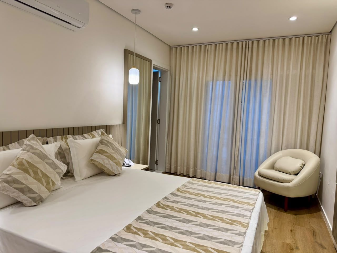Habitación de hotel con una cama grande, una silla, una puerta y cortinas.