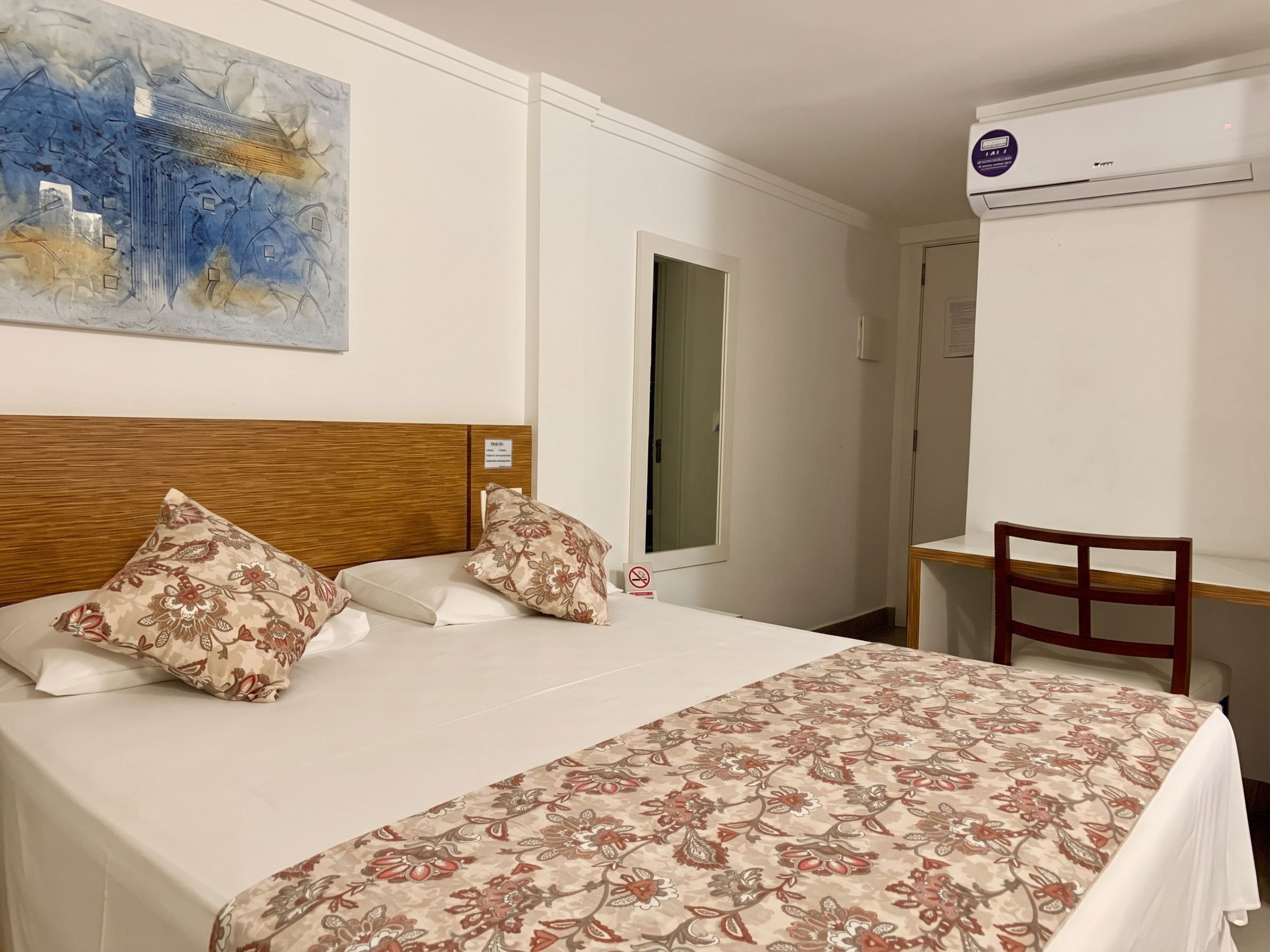 A hotel room with a bed, a desk, and a chair.