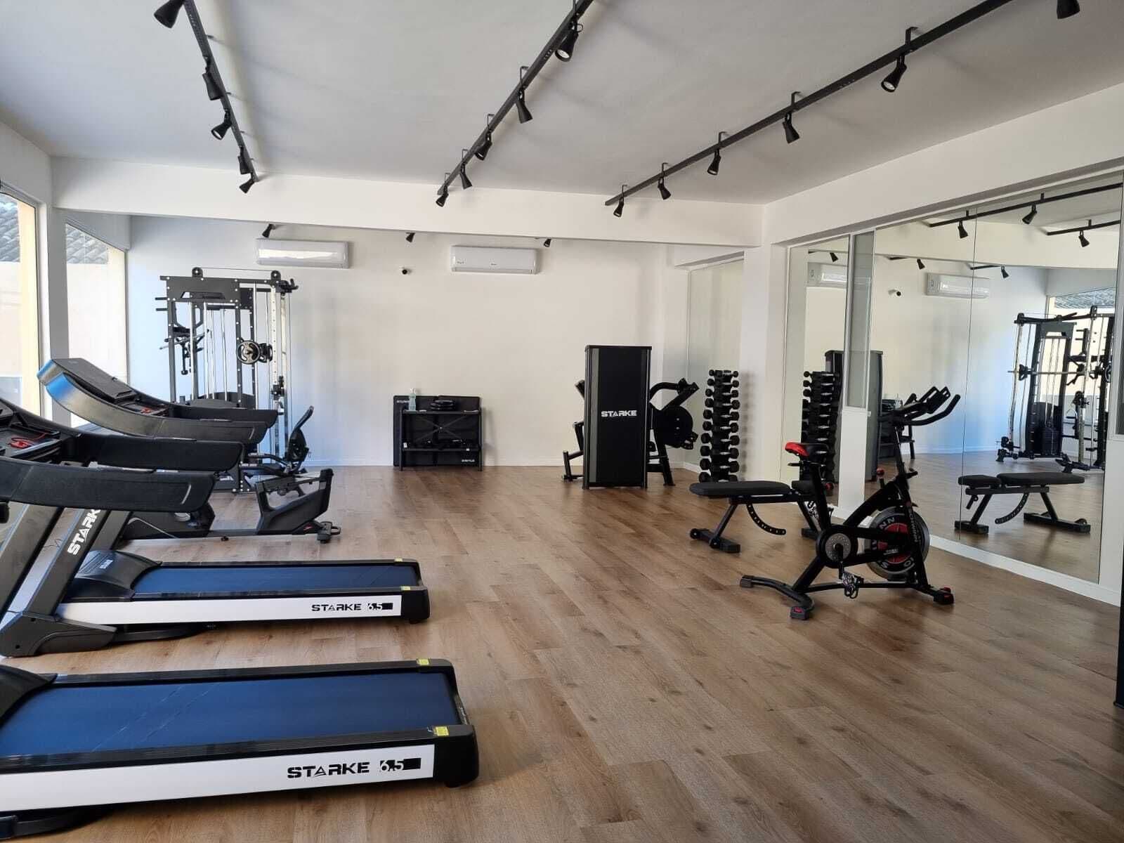 A gym with treadmills, weight machines, and a mirrored wall.