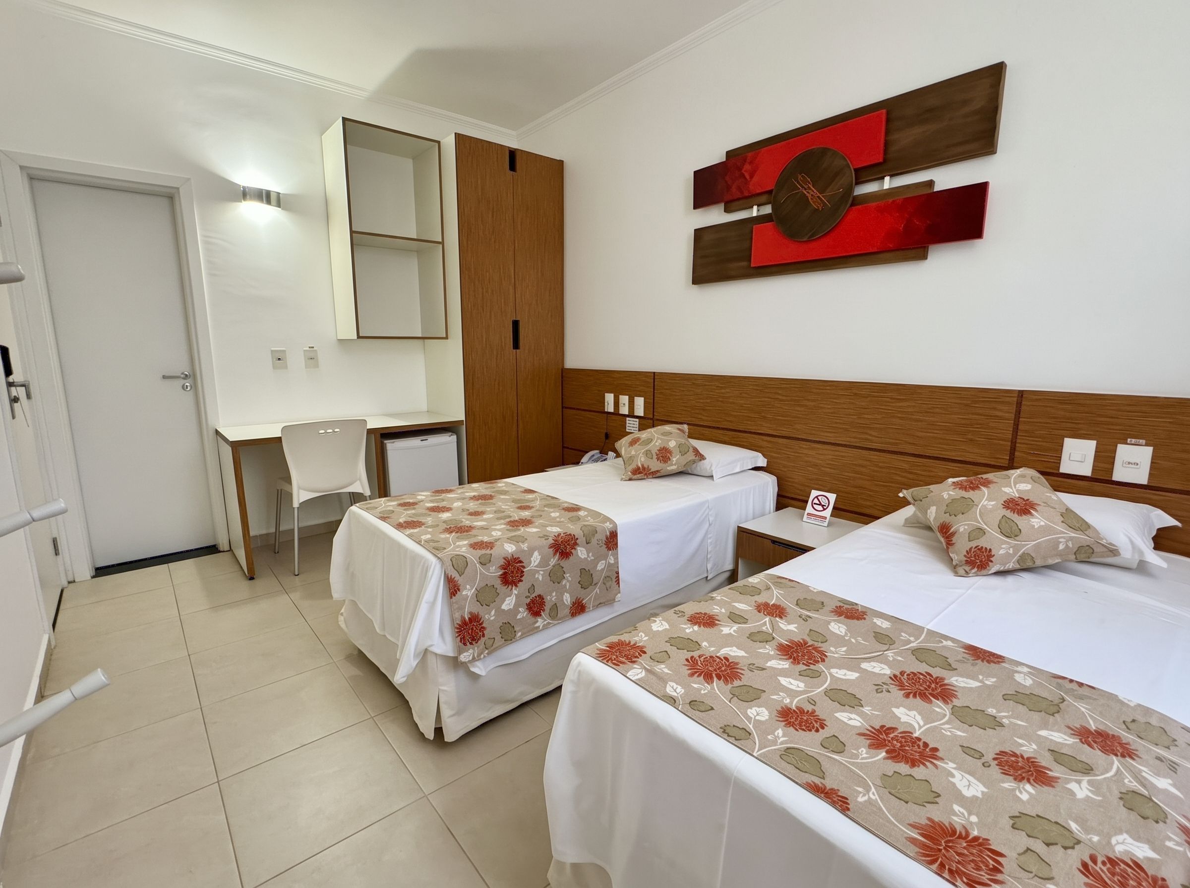 A hotel room with two beds, a desk, and a wardrobe.
