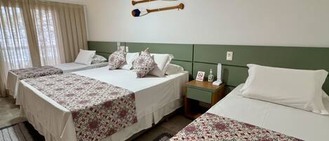 A hotel room with three beds, a nightstand, a wall-mounted air conditioner, and a window with curtains.