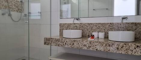 A modern bathroom with a glass shower enclosure, granite countertop, and two white sinks.