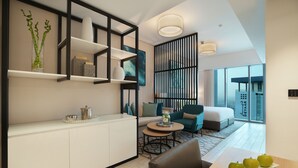 Une chambre d’hôtel moderne dotée d’un coin cuisine, d’une table à manger avec des pommes, d’un canapé et d’une grande fenêtre donnant sur la ville.