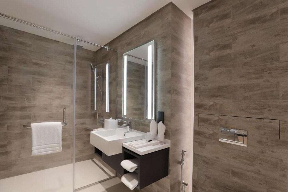 A modern bathroom with a glass shower enclosure, two sinks, and a large mirror.