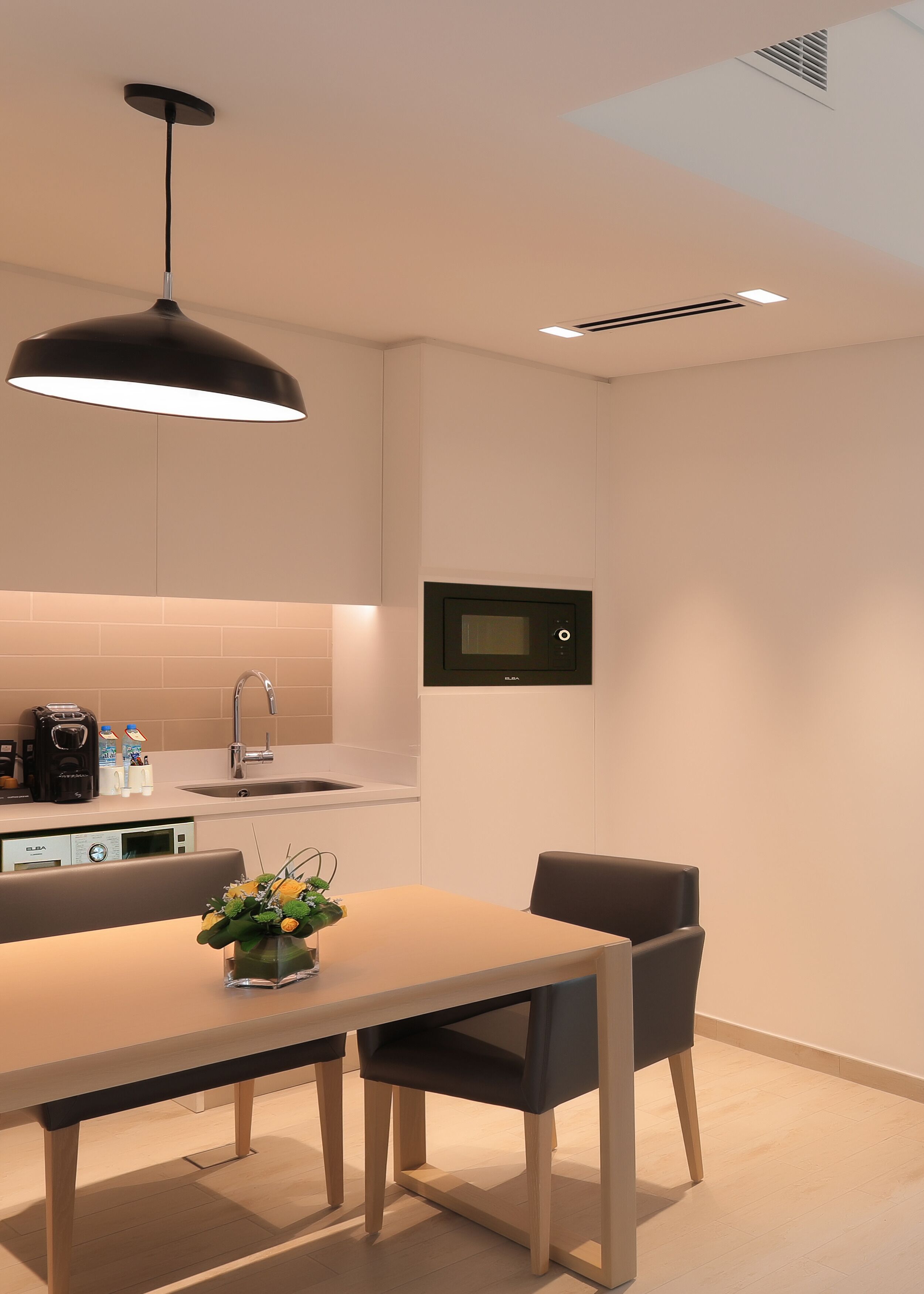 A modern kitchen with a built-in microwave, a coffee machine, and a sink.