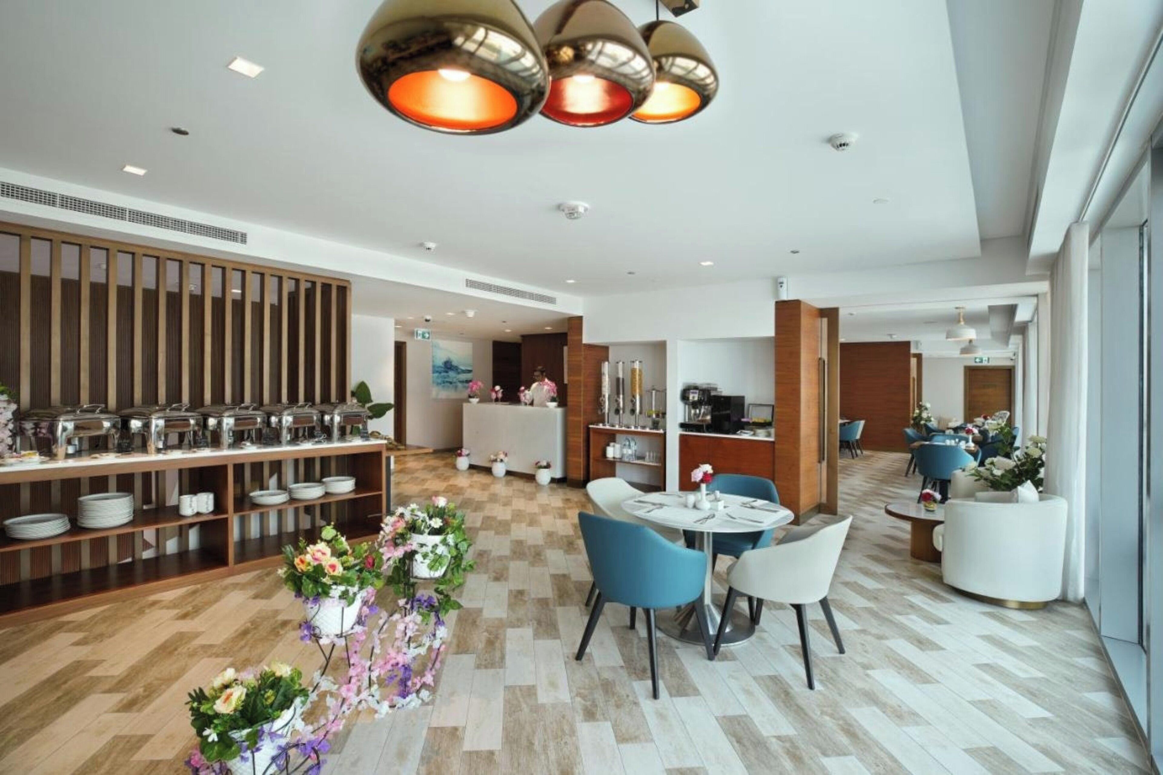 Un hall d’hôtel moderne doté d’un espace salon central, d’un comptoir d’accueil et d’un buffet.
