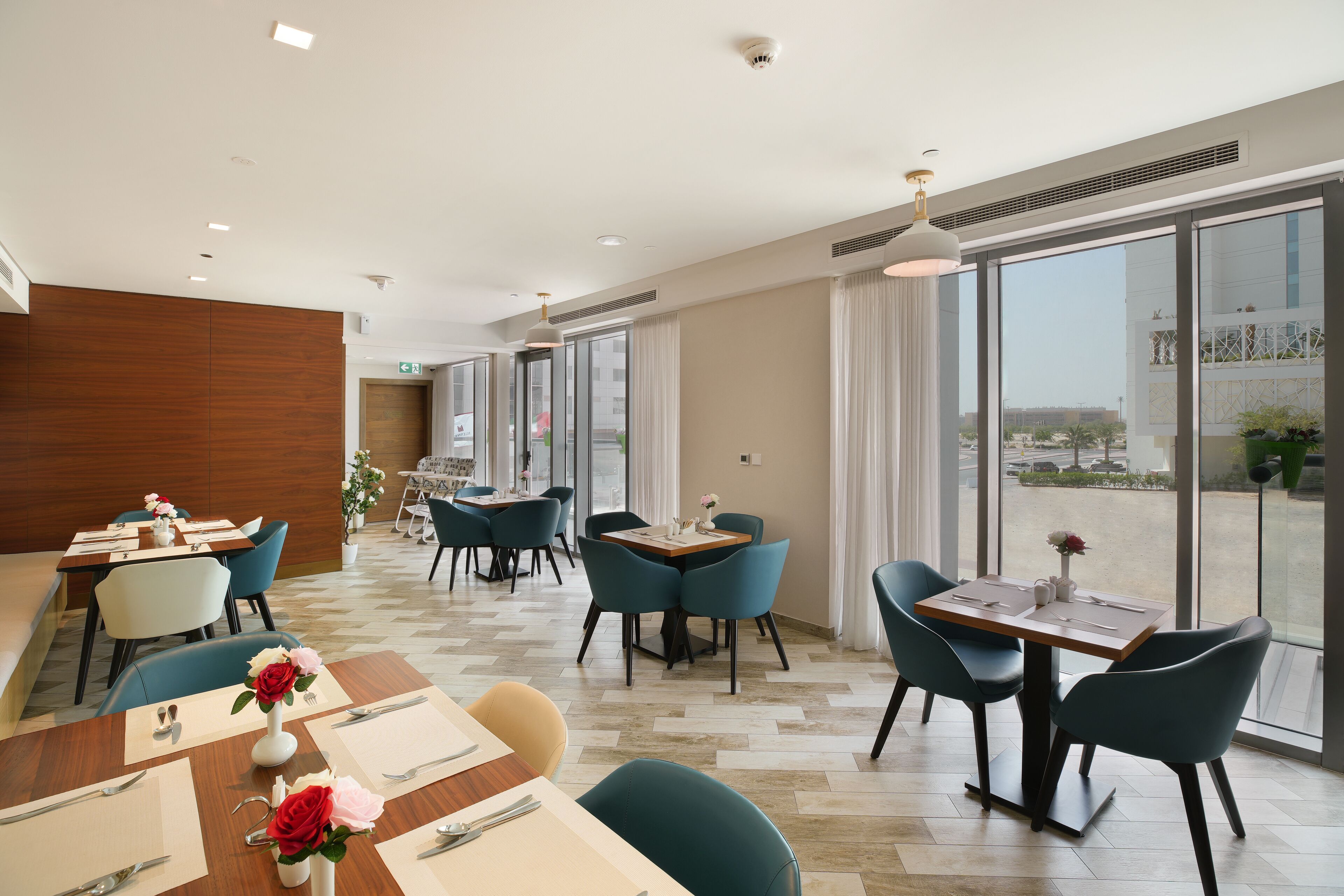 Un espace de restauration moderne, doté de tables et de chaises, de grandes fenêtres et offrant une vue sur la ville.