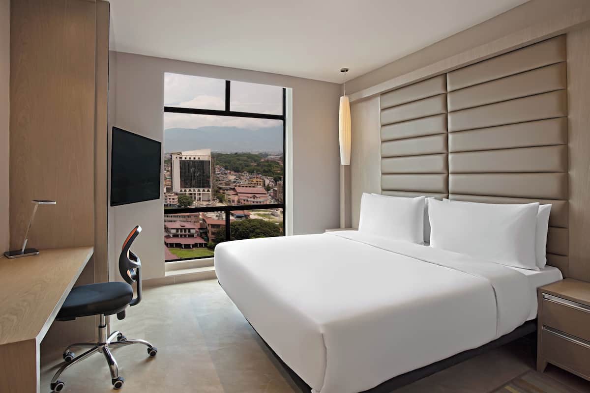 Une chambre d’hôtel avec un grand lit, un bureau, une chaise et un téléviseur.