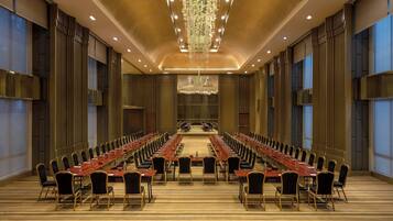 Uma sala de conferências com uma mesa comprida, cadeiras e um candelabro.