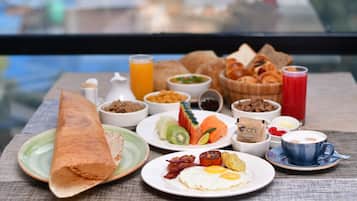 Una mesa con una variedad de platillos para el desayuno, incluyendo una crepe enrollada, huevos, tostadas y una taza de café.