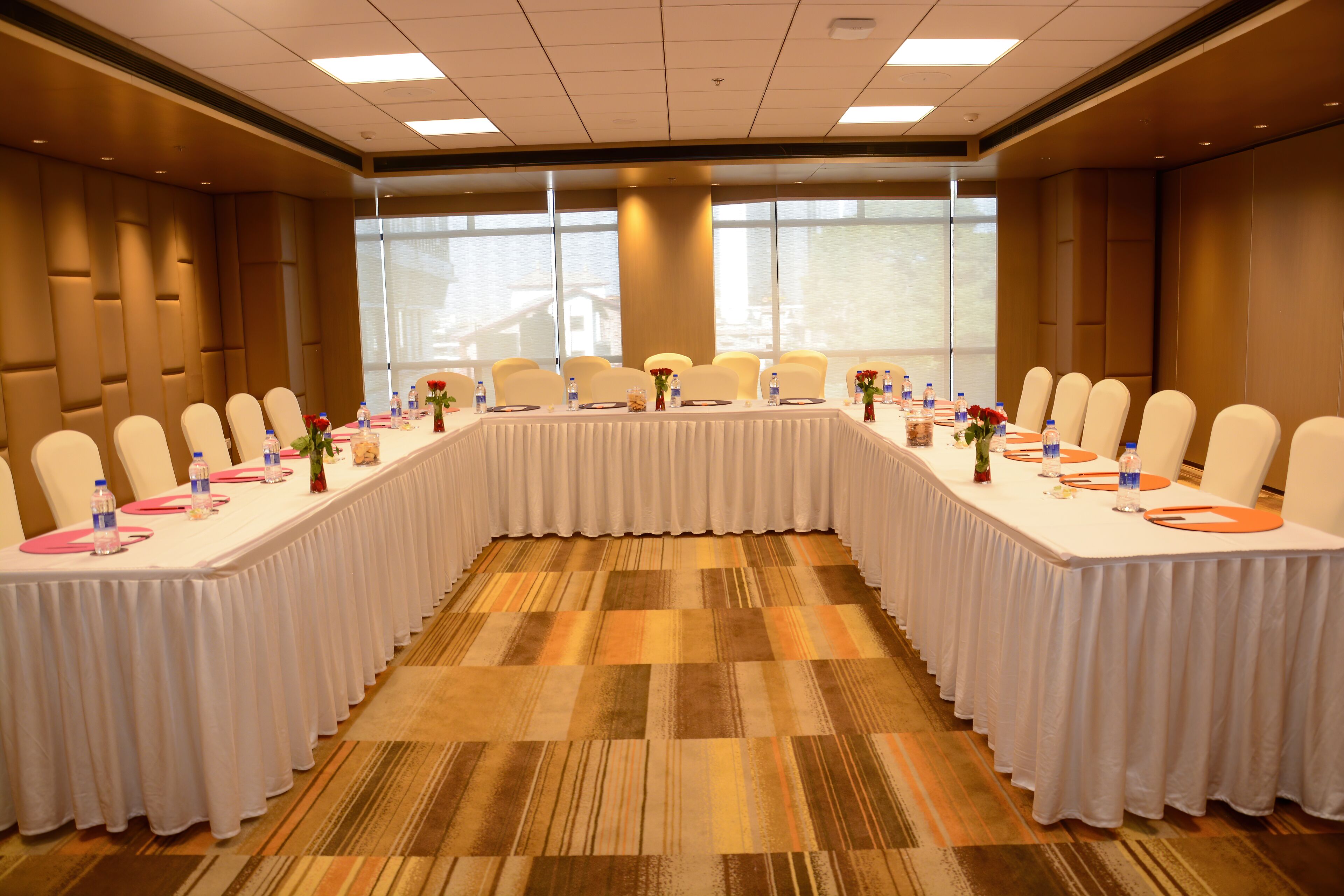 A conference room with a long table, white chairs, and water bottles.
