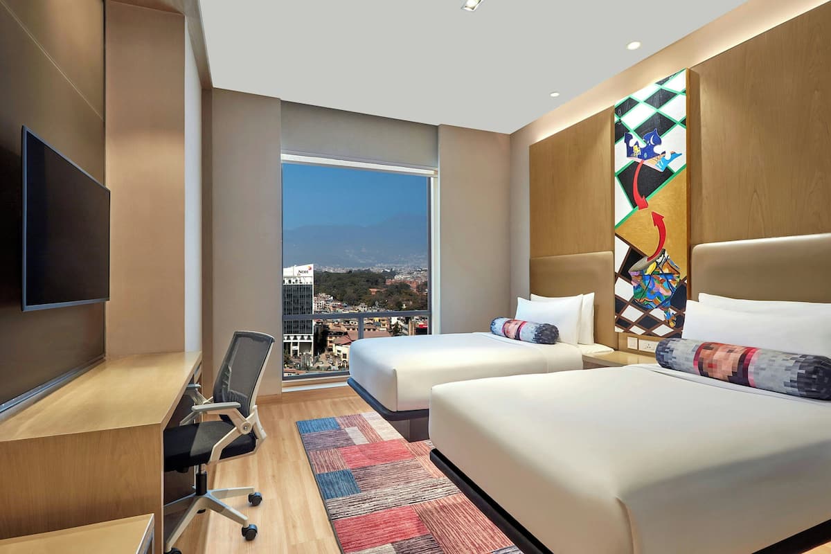 Une chambre d’hôtel avec deux lits, un bureau, une chaise et un téléviseur.
