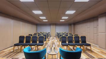 A conference room with rows of chairs, a wooden floor, and a ceiling with lights.