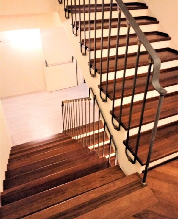 A wooden staircase with metal railings leading to a landing.