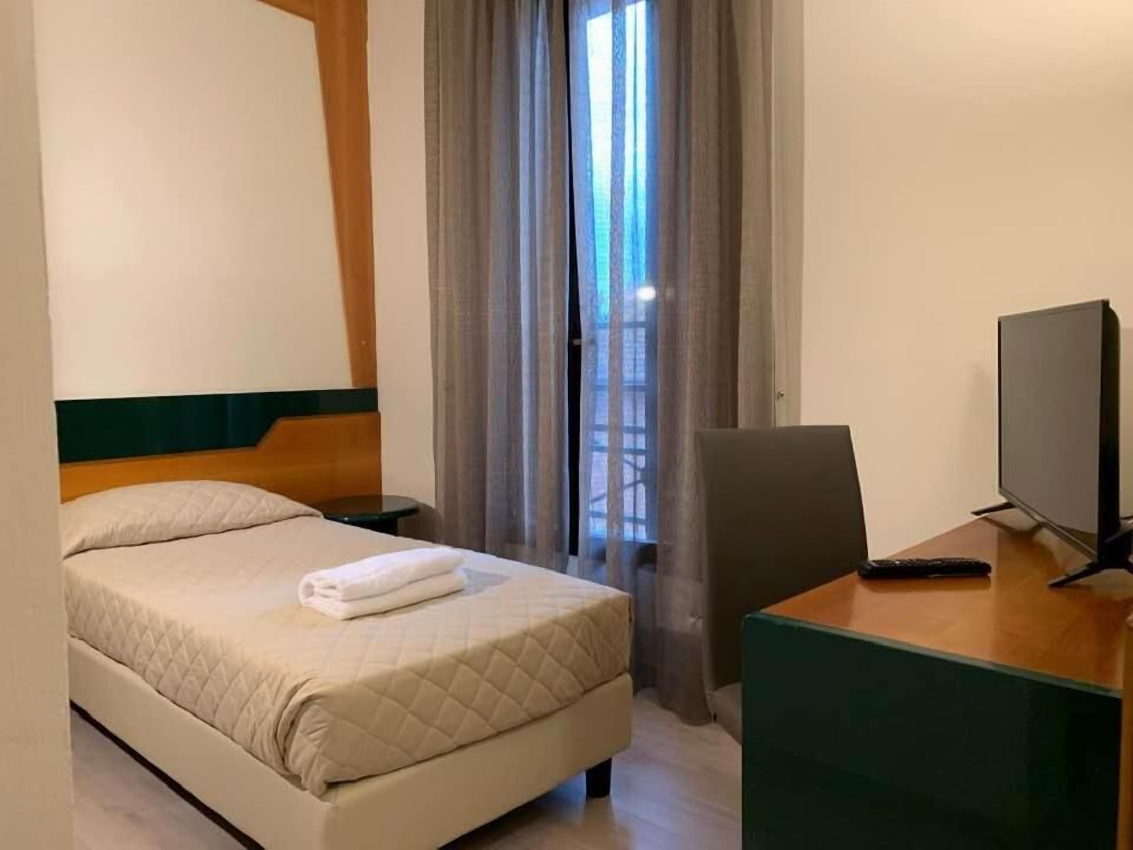 Een hotelkamer met een bed, bureau, stoel en televisie.