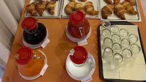 A buffet table with various food items including pastries, condiments, and beverages. - Hotel Dozza (Dozza)