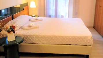 Ein Hotelzimmer mit einem Bett, einem Nachttisch mit einer Lampe und einer Vase mit Blumen.