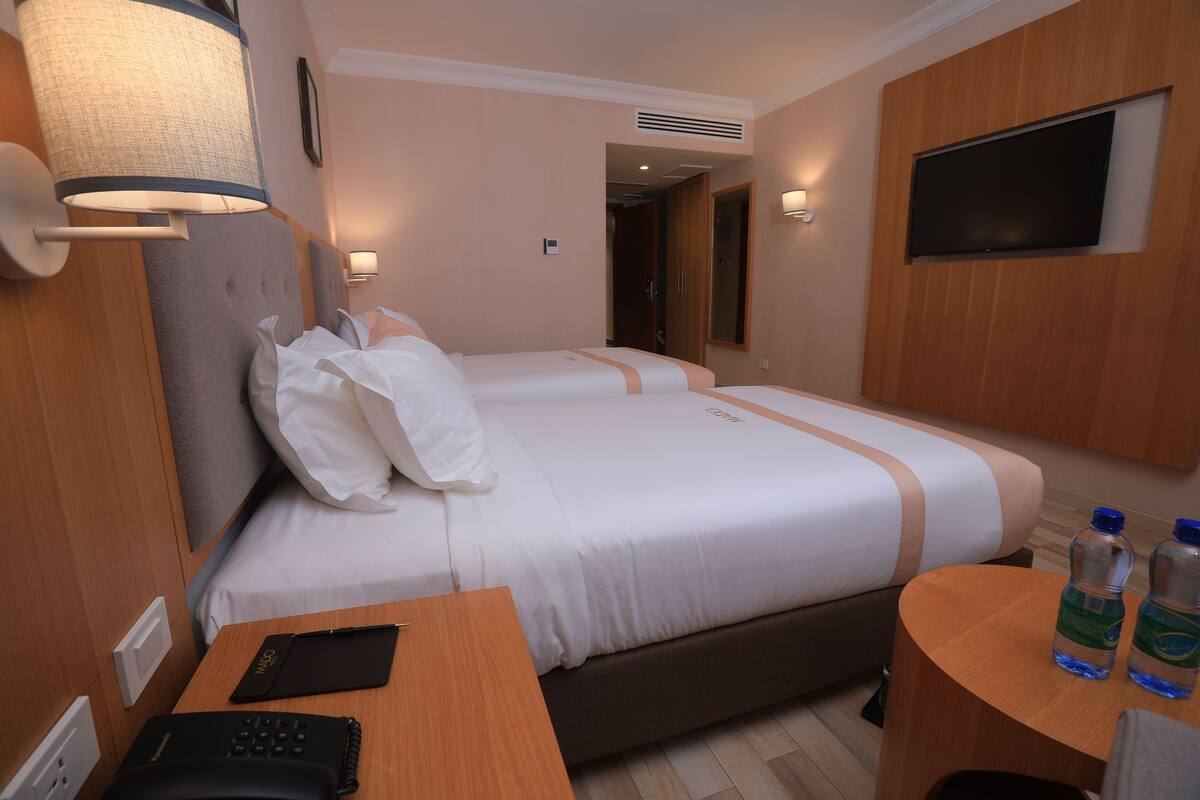Habitación de hotel con dos camas, un escritorio con teléfono y una mesa con botellas de agua.