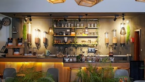 Una zona de bar con estantes llenos de copas, un mostrador de madera y lámparas colgantes.