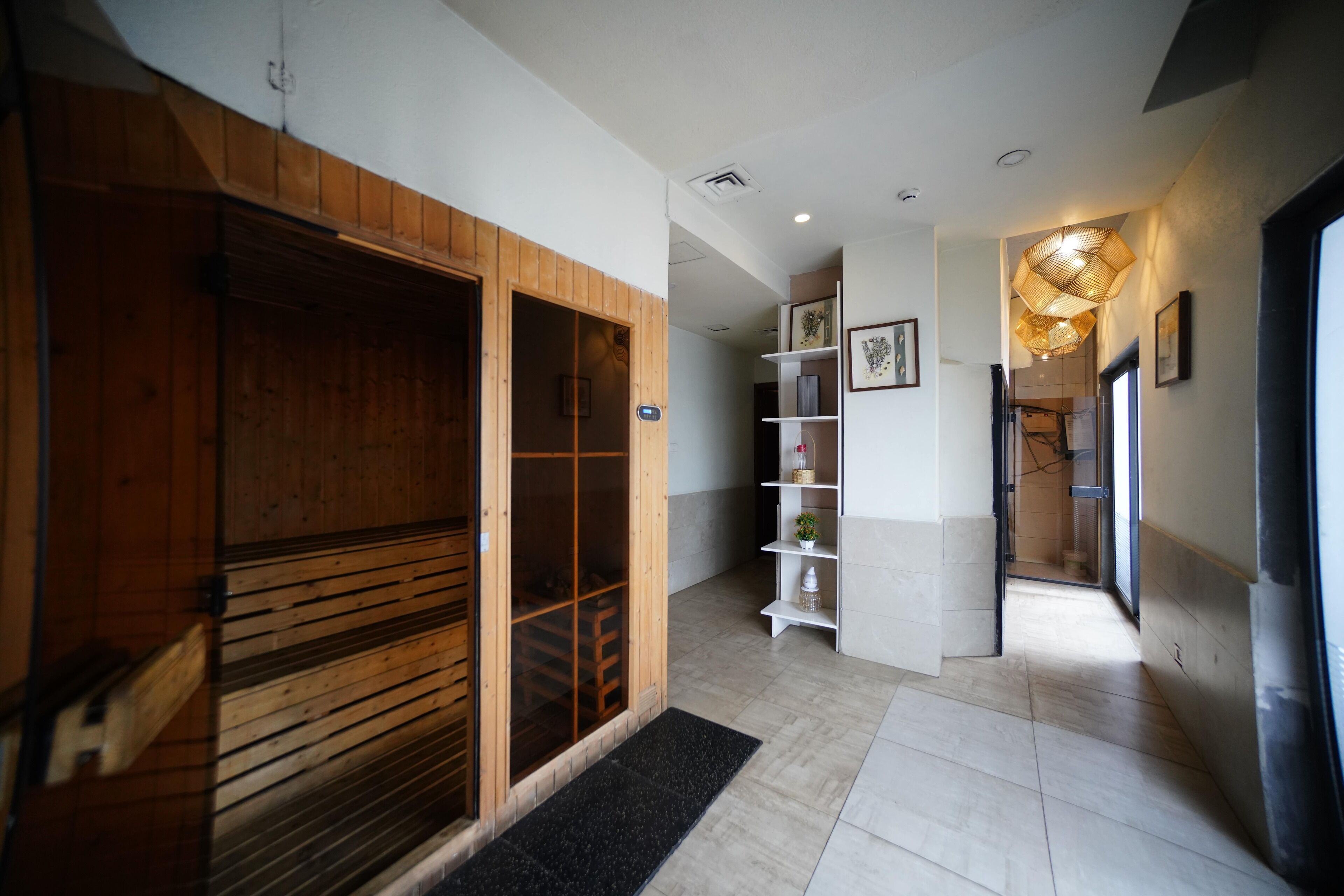A hallway with a wooden door, a white shelf with decorative items, and a modern light fixture.
