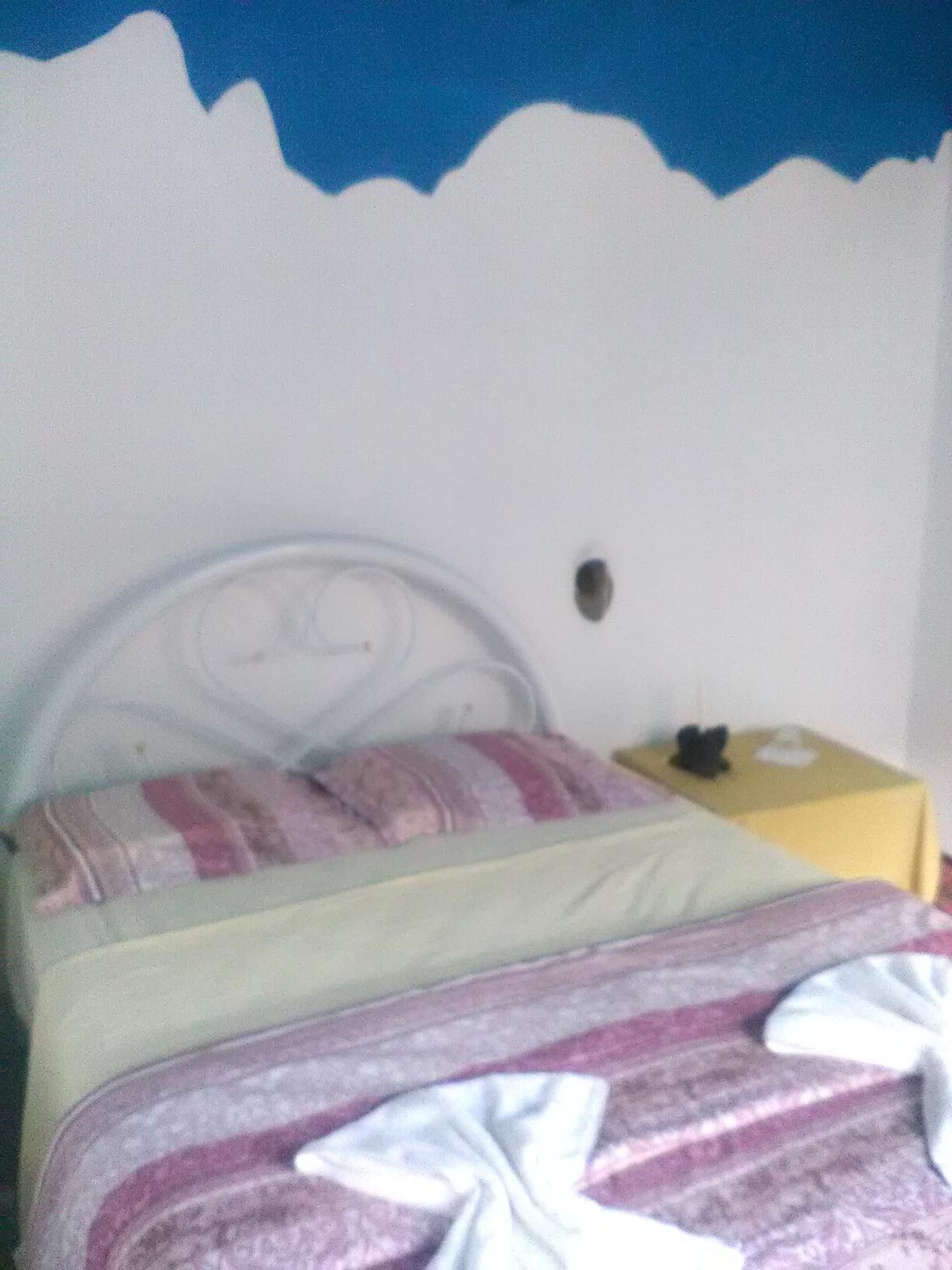 A bedroom with a bed, a nightstand, and a wall with a blue and white pattern.