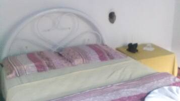 A bedroom with a bed, a nightstand, and a wall with a blue and white pattern.