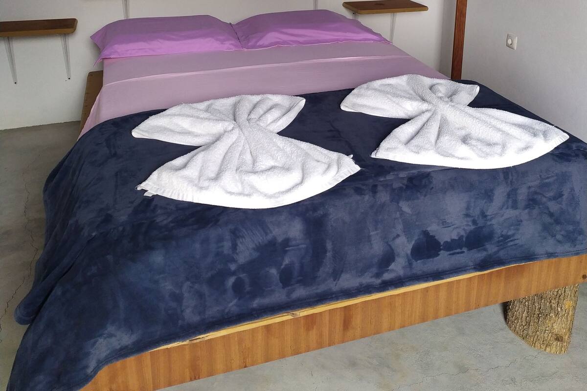 A bed with a blue and purple bedspread, white towels, and wooden headboards.